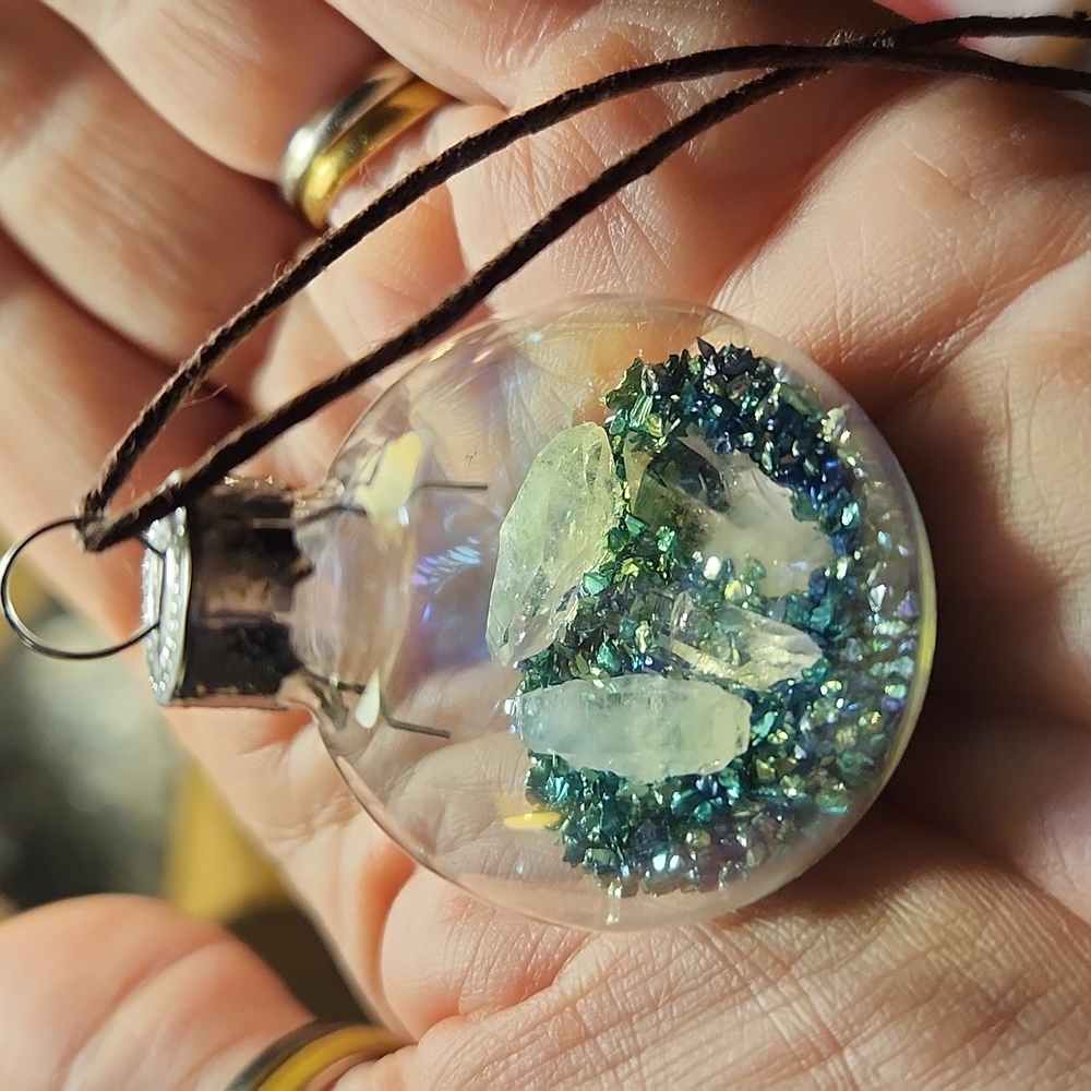 Ornament glass ball with green glass confetti and four raw crystals.